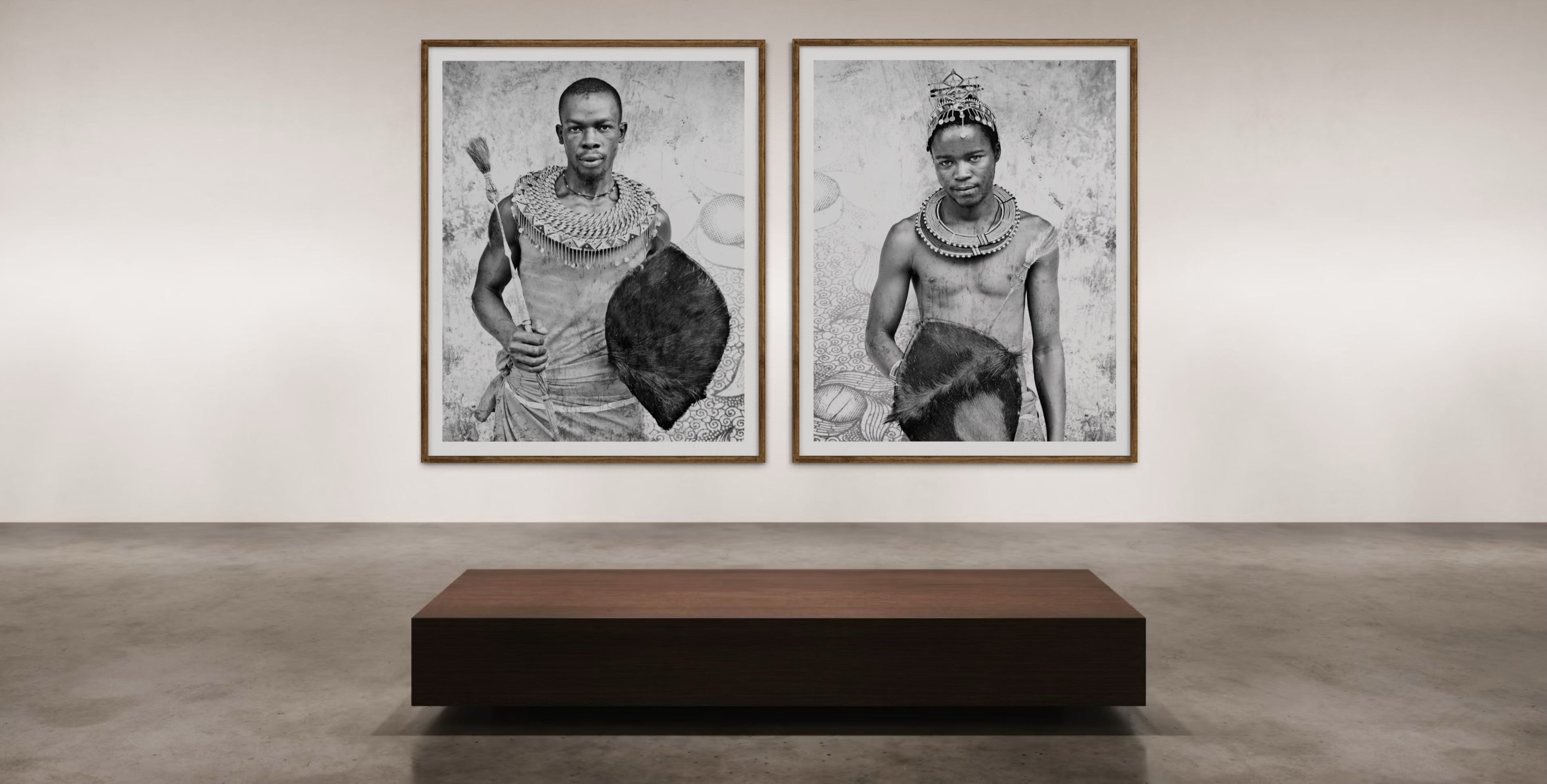 Two framed black and white portraits artworks on a wall in an art gallery.